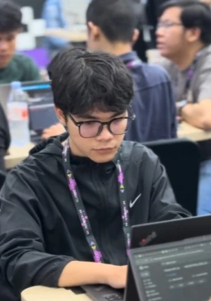 Anggara at a hackathon, working on a laptop